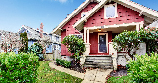 A red sided home in a neighborhood, that could use some fixing. 